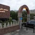 سردر ورودی مجتمع گردشگری با طاق آجری، دیوار آجری و محوطه‌سازی سبز در نمای بیرونی